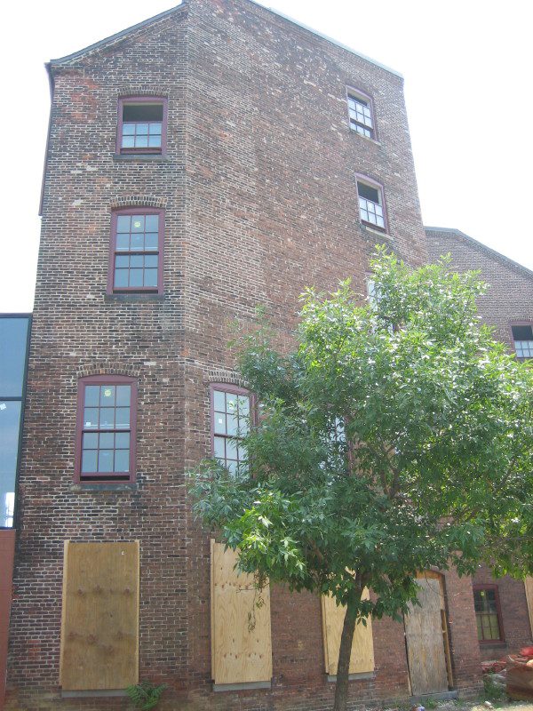 A brick building with the windows boarded up.